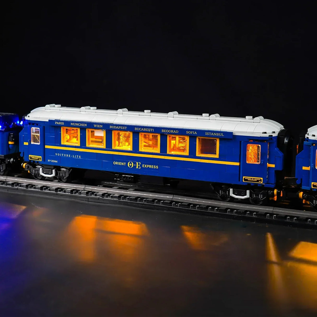 Beleuchteter Modellbauwagen des Orient Express auf Schienen vor schwarzem Hintergrund
