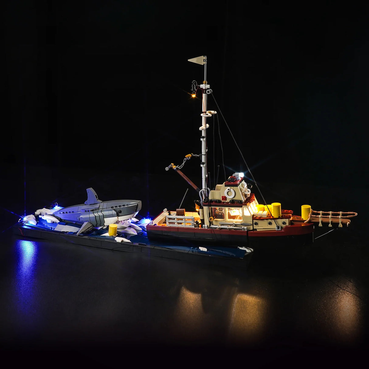 Beleuchtetes Lego Modell eines Fischerbootes mit einem Hai im Wasser vor schwarzem Hintergrund