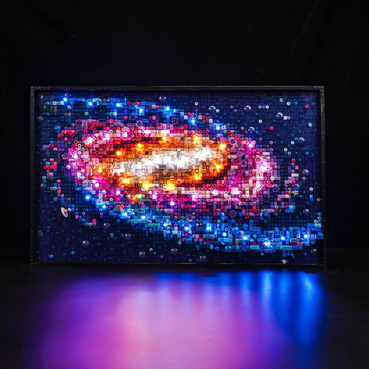 Beleuchtetes Wandbild aus Lego Steinen in Form einer bunten Galaxie vor schwarzem Hintergrund