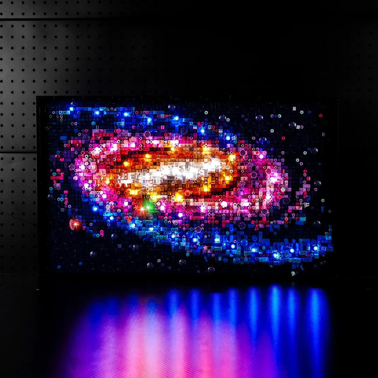 Beleuchtetes Lego Kunstwerk einer bunten Spiralgalaxie vor schwarzem Hintergrund