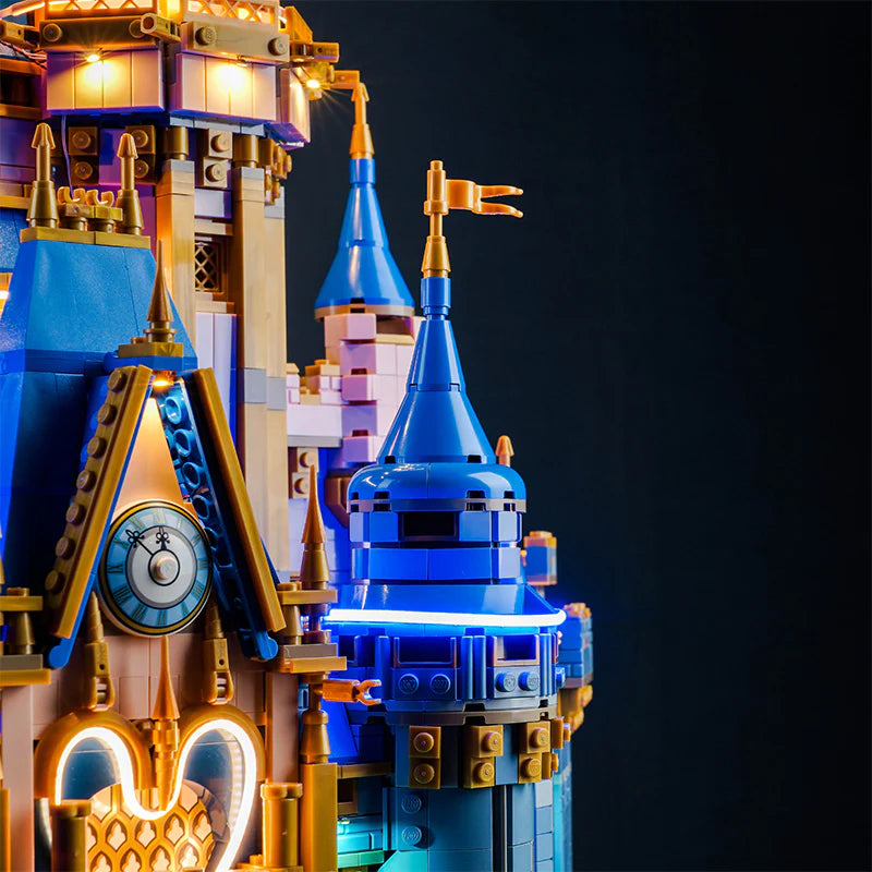 Beleuchtetes Lego Schloss mit Uhrturm und blauen Turmspitzen vor dunklem Hintergrund