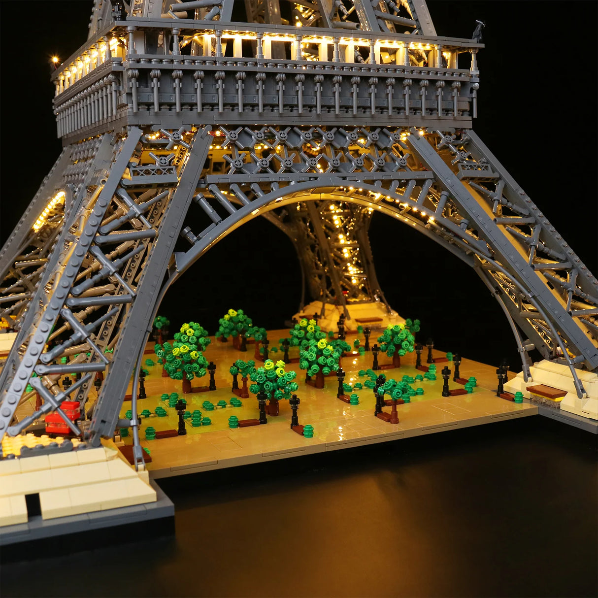 Unterer Bogen des LEGO Eiffelturms 10307 mit LED-Lichterkette, Esplanade mit Miniatur-Bäumen und Straßenlaternen im Detail. 44883432702180