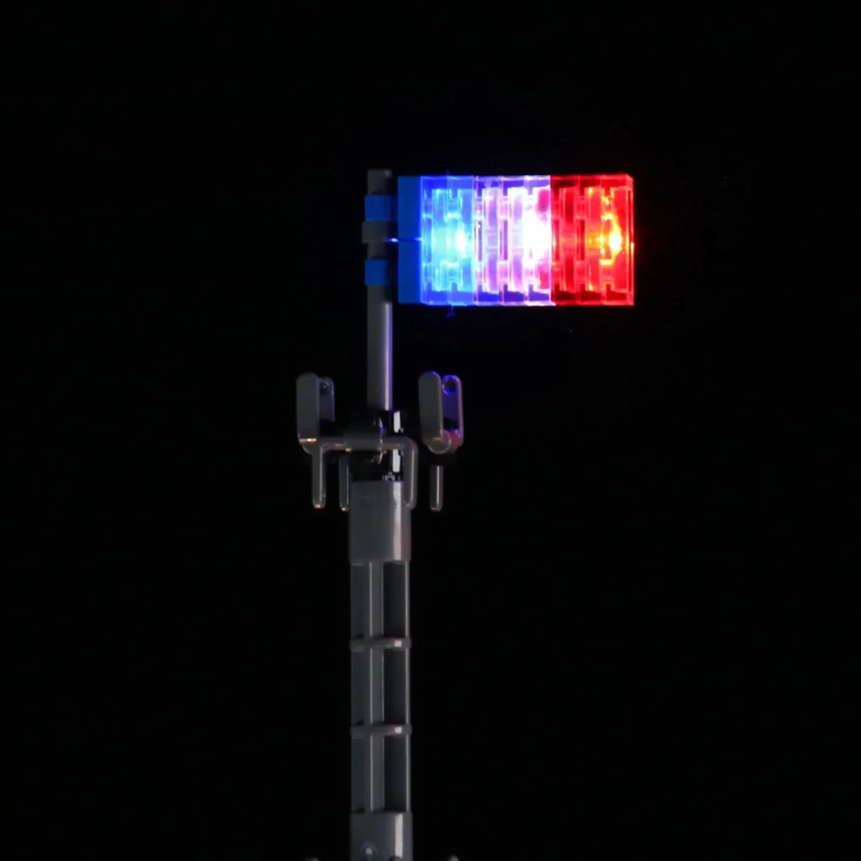 Nahaufnahme der LEGO Eiffelturm-Spitze mit einer durch LED-Lichter beleuchteten Tricolore-Flagge in Blau, Weiß und Rot. 44883432734948