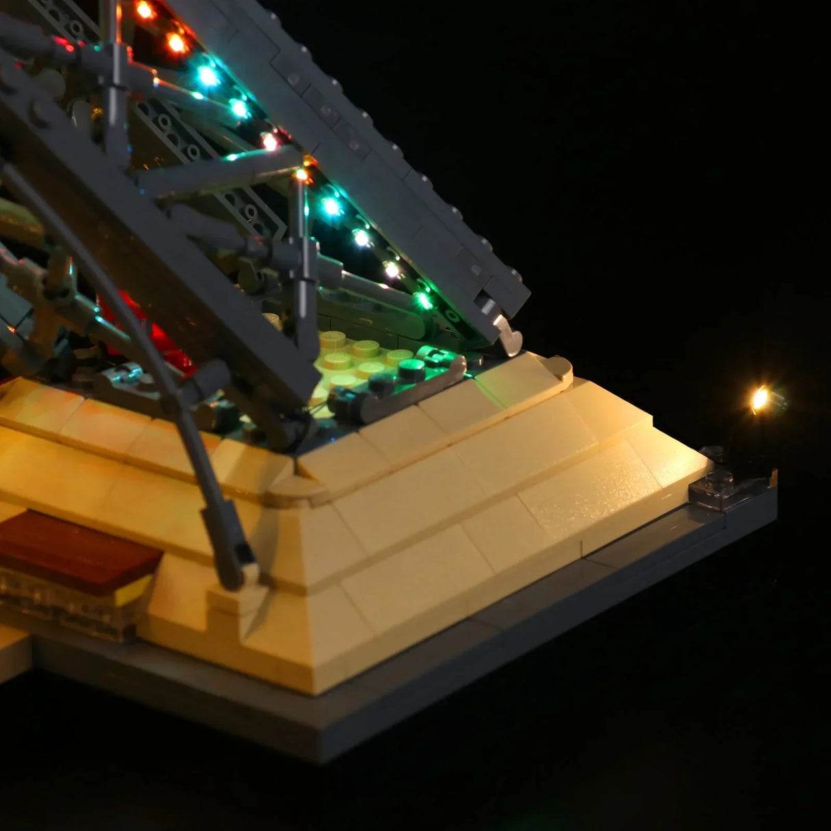 Detailansicht eines LEGO Eiffelturm-Standfußes mit bunten, funkelnden RGB-LED-Lichtern entlang der grauen Pfeilerstruktur. 44883432734948
