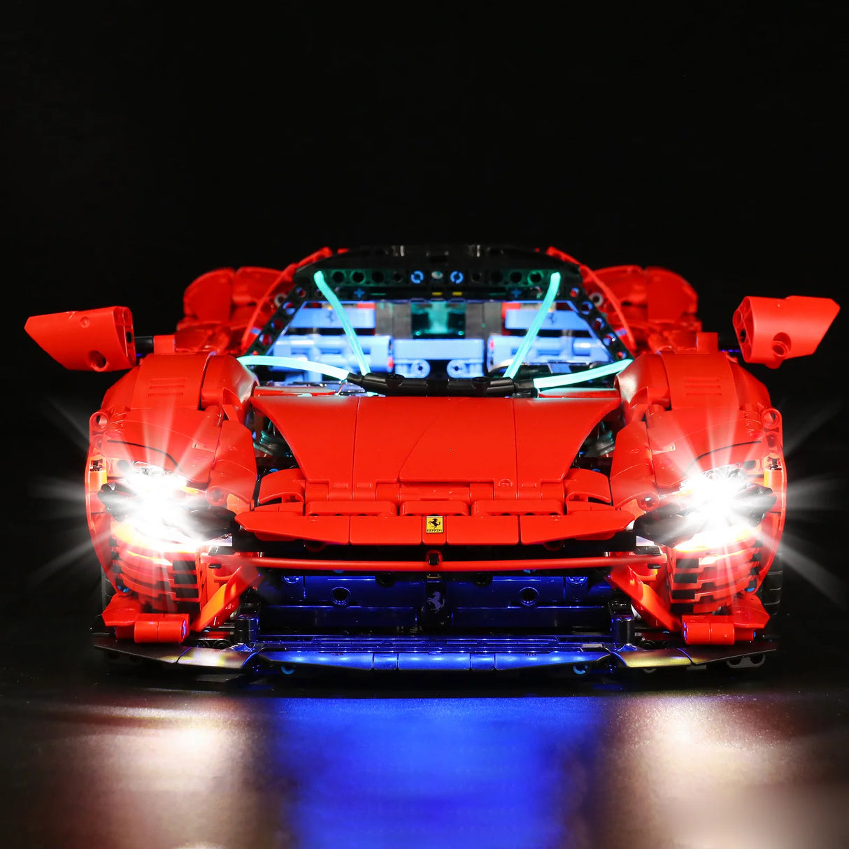 Rotes Lego Ferrari Modellauto mit eingeschalteter LED Beleuchtung vor schwarzem Hintergrund