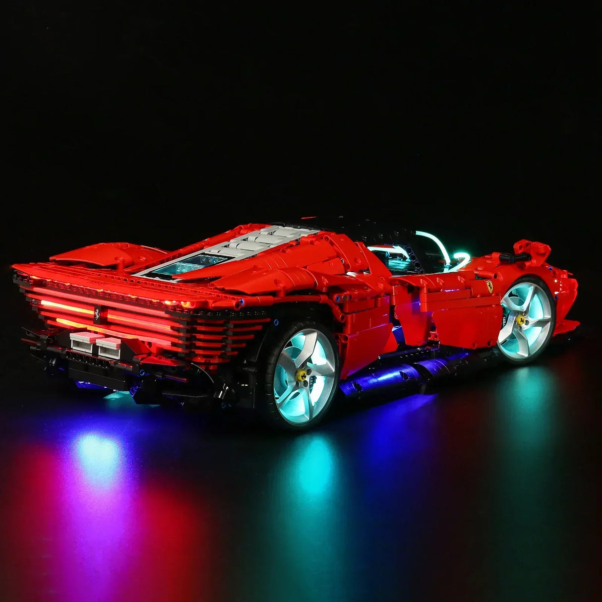 Rotes Ferrari Modellauto aus Klemmbausteinen mit blauer und roter LED Beleuchtung vor schwarzem Hintergrund
