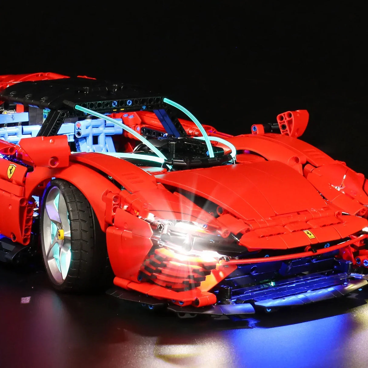 Rotes Ferrari Modellauto aus Klemmbausteinen mit leuchtenden Scheinwerfern vor schwarzem Hintergrund