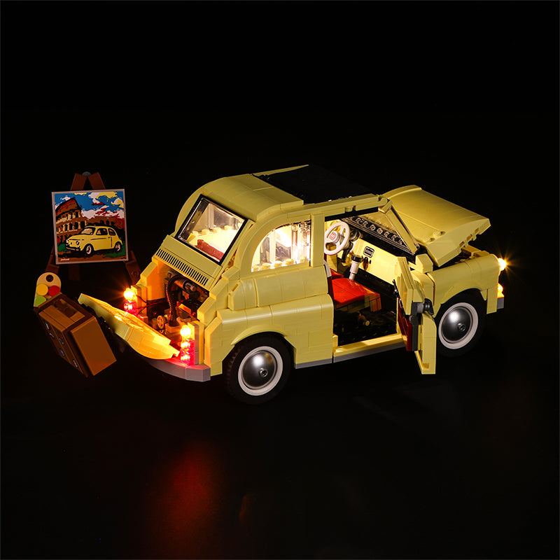 Beleuchtetes Lego Modell eines gelben Fiat 500 mit offenem Kofferraum und Koffer sowie Staffelei