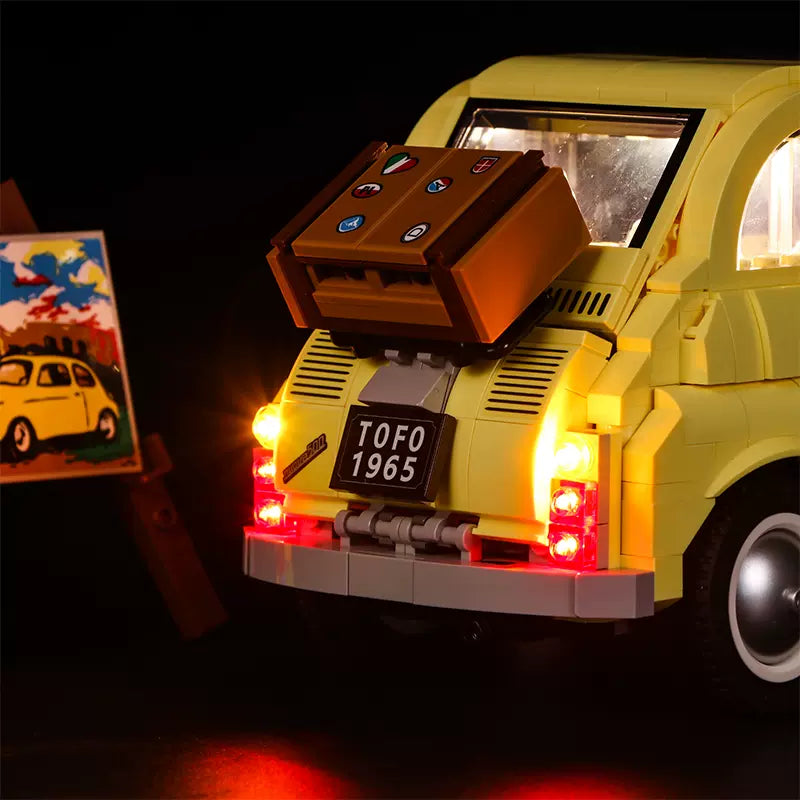Gelbes Lego Fiat 500 Modell mit beleuchteten Rücklichtern und einem Koffer auf dem Heckgepäckträger