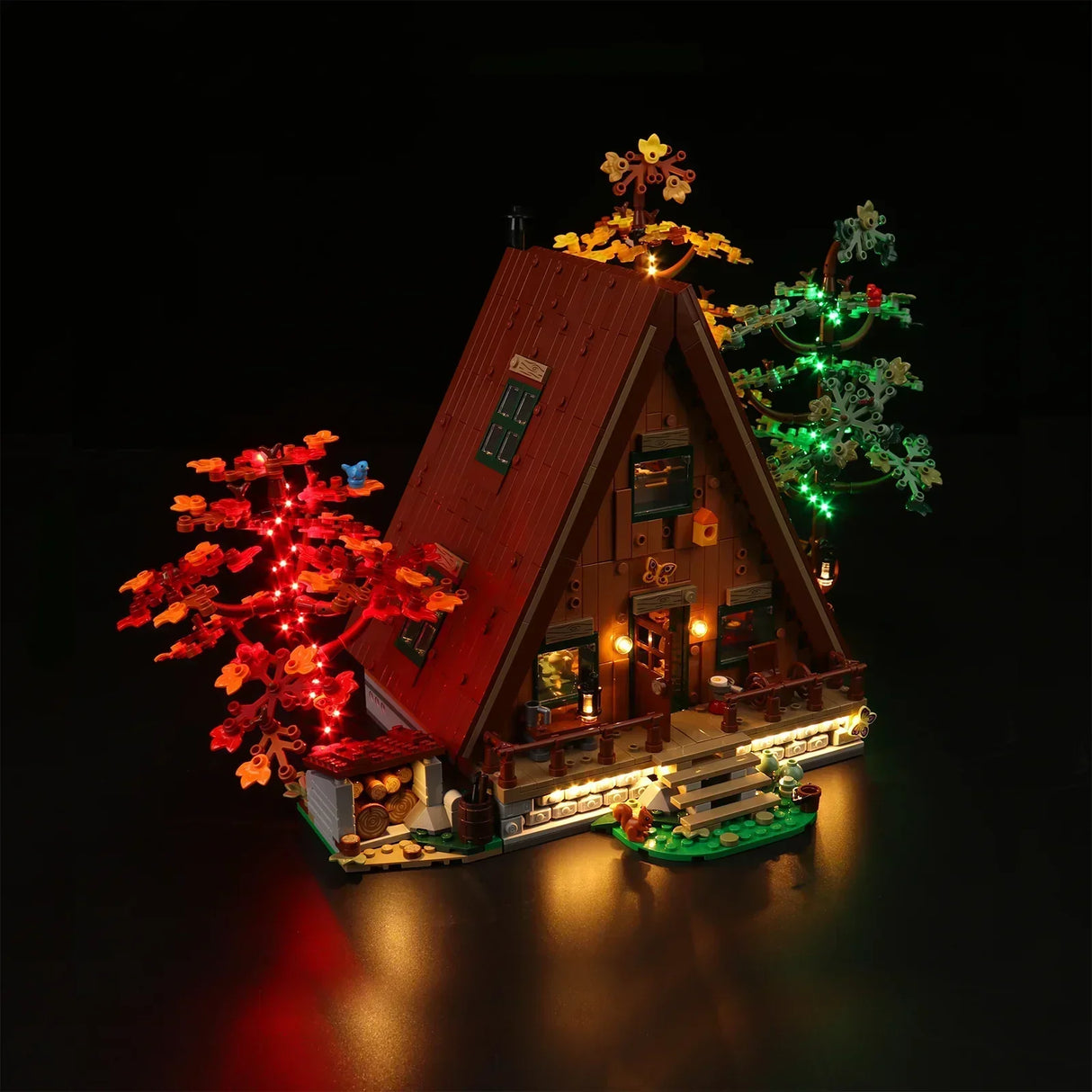 Beleuchtetes Lego A-Frame Haus mit Bäumen vor schwarzem Hintergrund