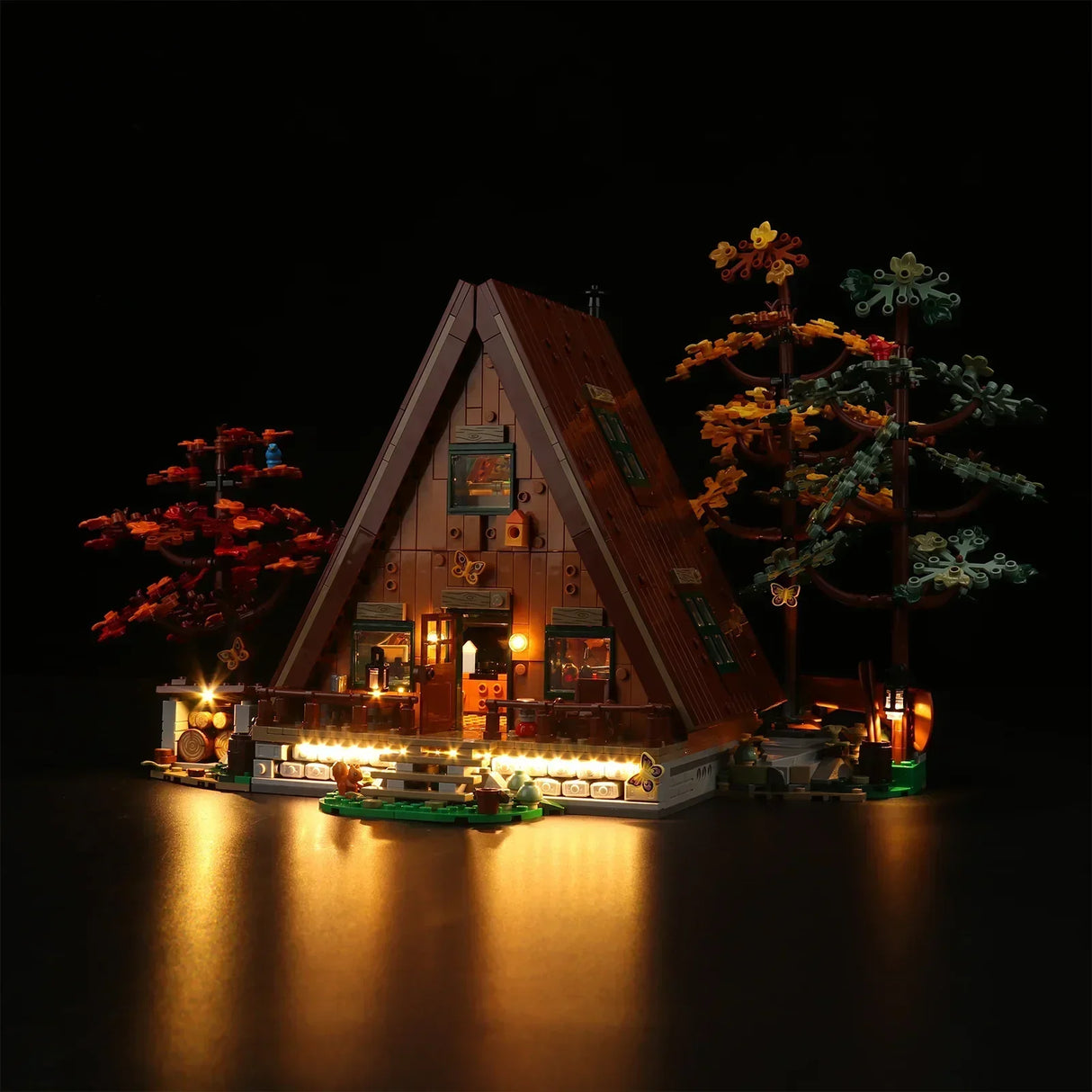 Beleuchtetes Lego A-Frame Haus Modell mit herbstlichen Bäumen vor schwarzem Hintergrund