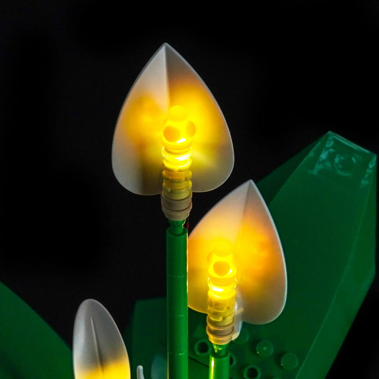 Leuchtende LEGO-Pflanzen mit gelben Blüten und grünen Stielen auf schwarzem Hintergrund