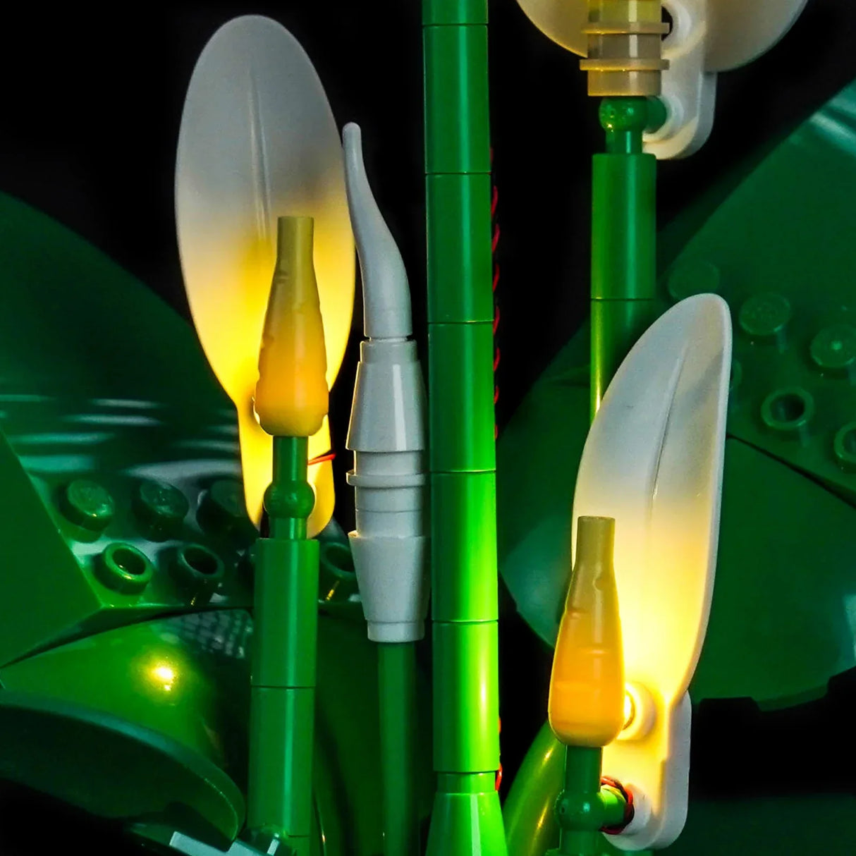 Nahaufnahme einer LEGO-Orchidee mit grünen Stielen, weißen Blütenblättern und gelben Blütenknospen