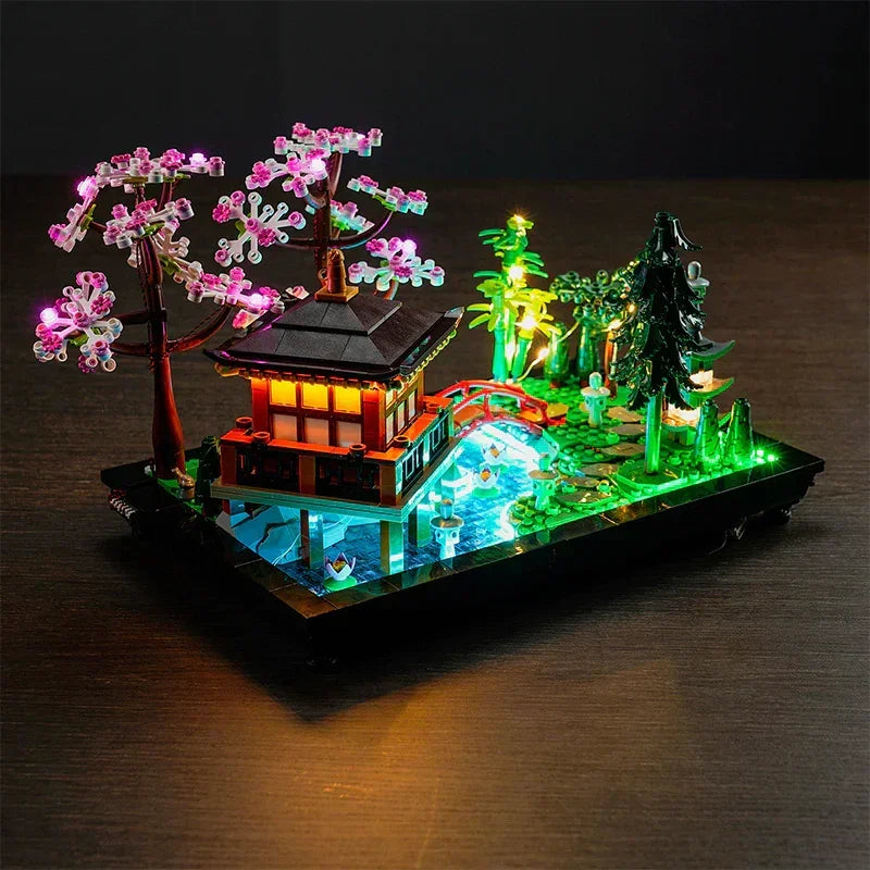 Gesamtansicht des LEGO 10315 Sets auf einem dunklen Holztisch, inszeniert mit einem LED-Lichtkit, das den japanischen Garten im Dunkeln leuchten lässt.
