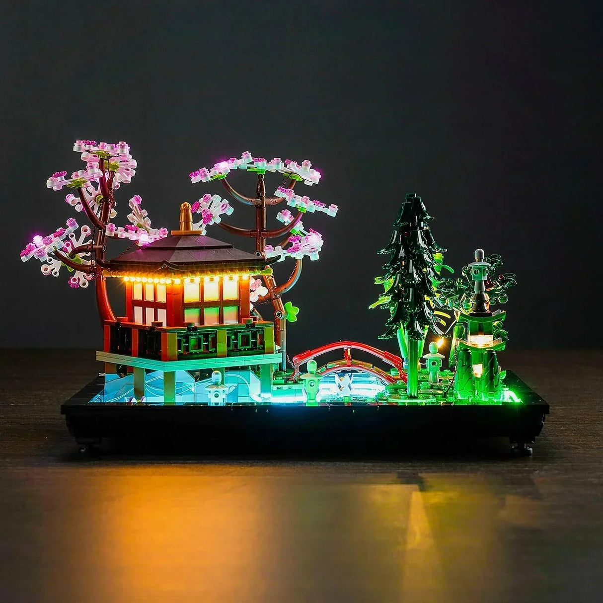 Frontalansicht des LEGO Icons Sets Garten der Stille (10315) mit aktiviertem LED-Beleuchtungsset, das die Kirschblütenbäume, Brücke und Teepavillon illuminiert.