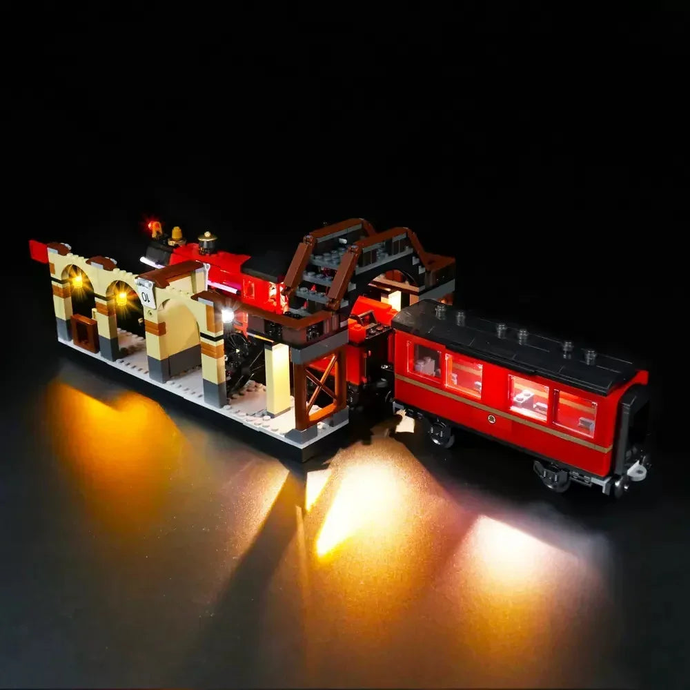 Beleuchtetes Lego Zugmodell mit Bahnhofsgebäude vor schwarzem Hintergrund