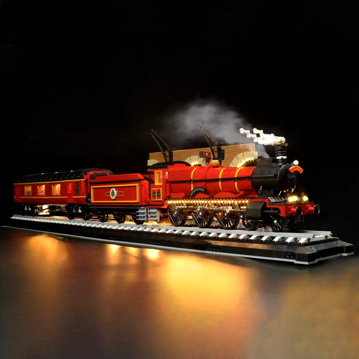 Beleuchtetes Lego Modell des Hogwarts Express Zuges auf Schienen vor schwarzem Hintergrund