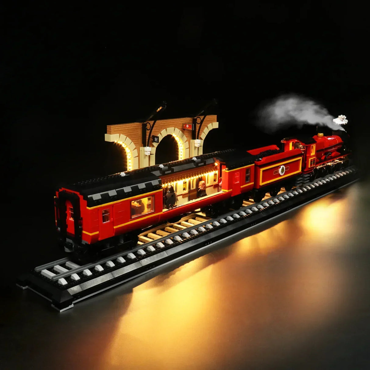 Beleuchtetes Lego Modell eines roten Zuges auf Schienen vor einem Bahnhofsbogen