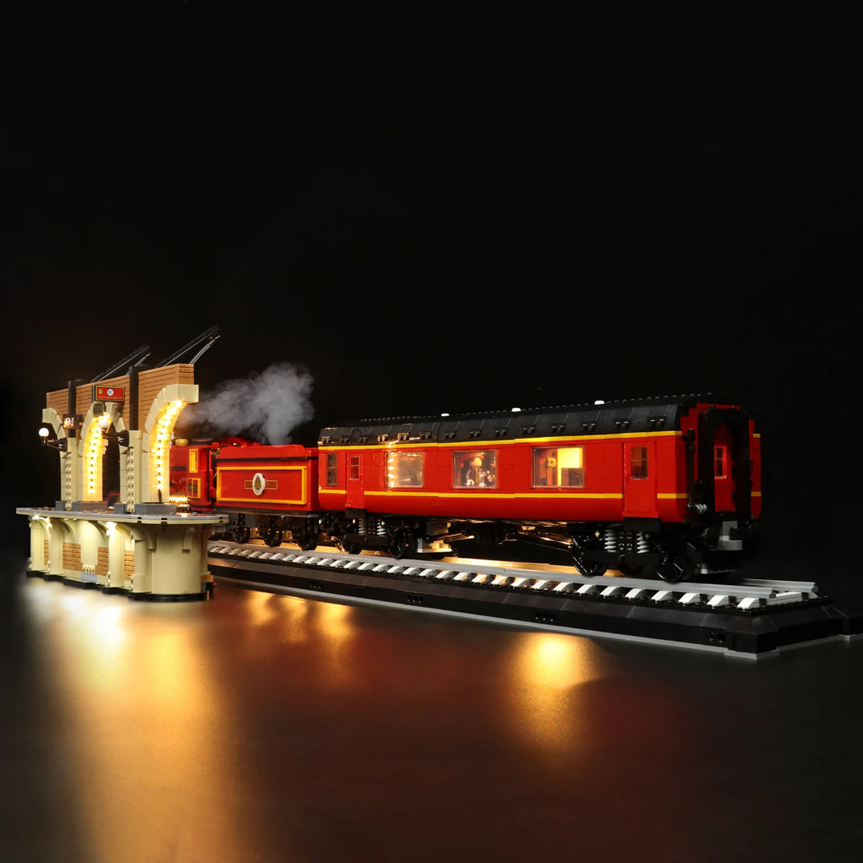 Beleuchtetes Lego Modell eines roten Zuges an einem Bahnsteig vor schwarzem Hintergrund