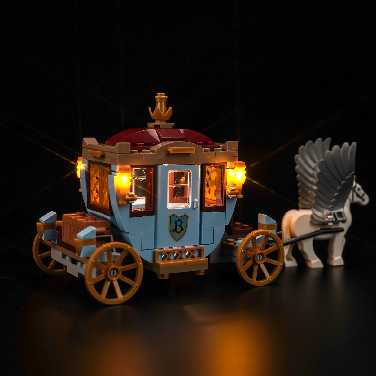 Beleuchtete Lego Kutsche mit einem geflügelten Pferd vor schwarzem Hintergrund