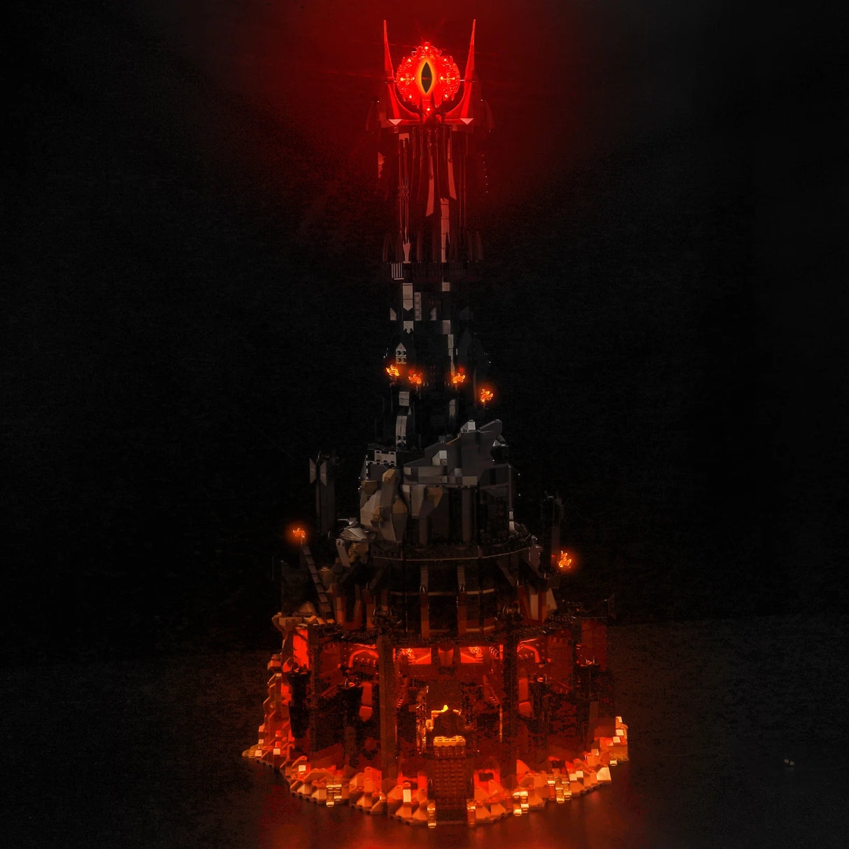 Beleuchtetes Lego Modell des Turms Barad-dur mit dem Auge von Sauron vor schwarzem Hintergrund