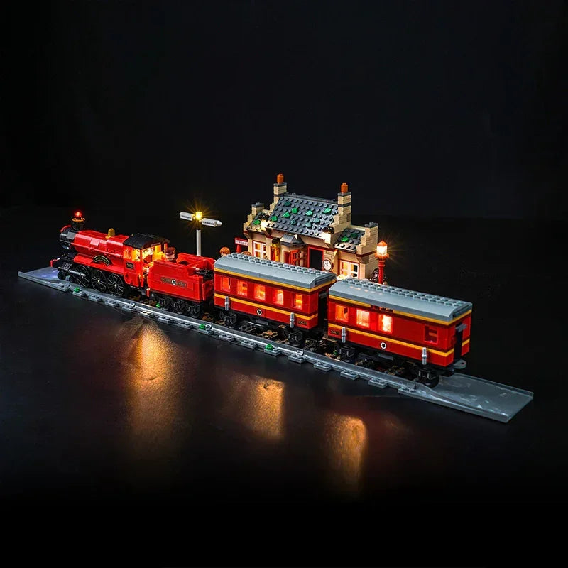 Beleuchtetes Lego Modell eines roten Dampfzuges mit Bahnhofsgebäude auf Schienen vor schwarzem Hintergrund