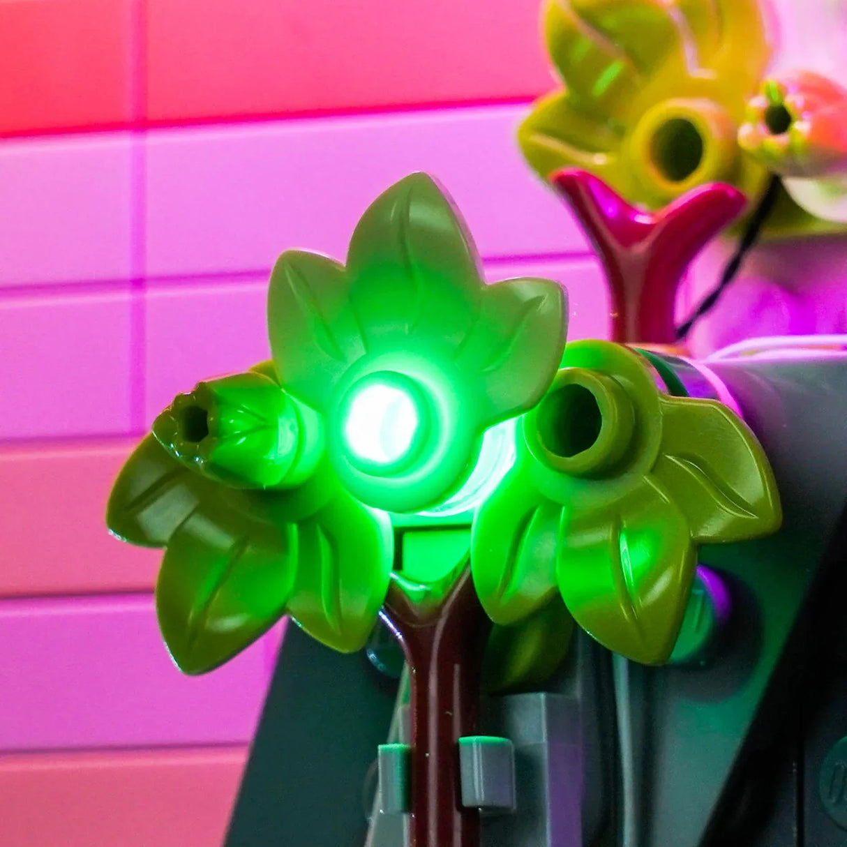 Nahaufnahme eines leuchtenden grünen Lego-Baumes mit rosa Hintergrund