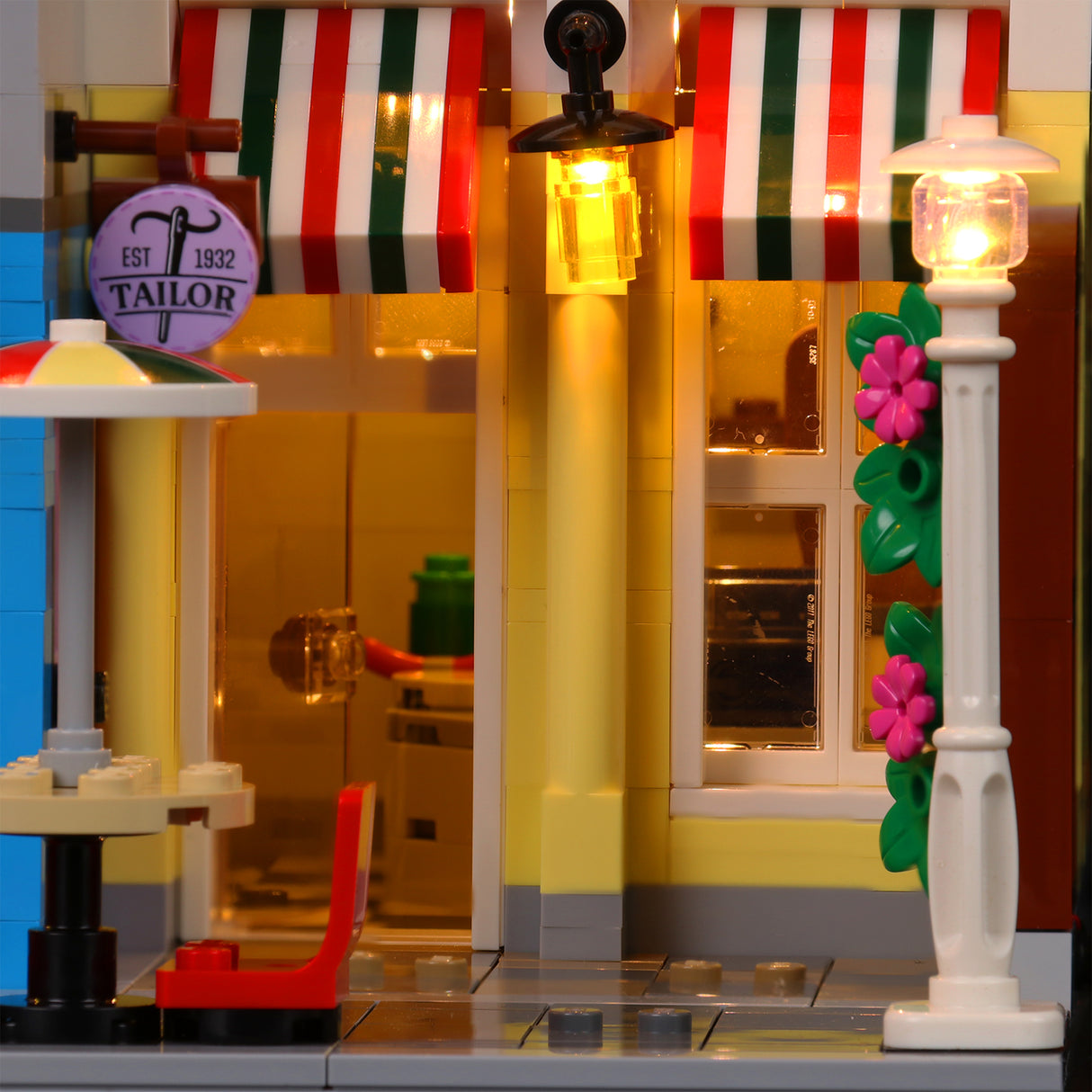 Beleuchtete Fassade eines Lego Schneidereigebäudes mit Markisen und Laterne