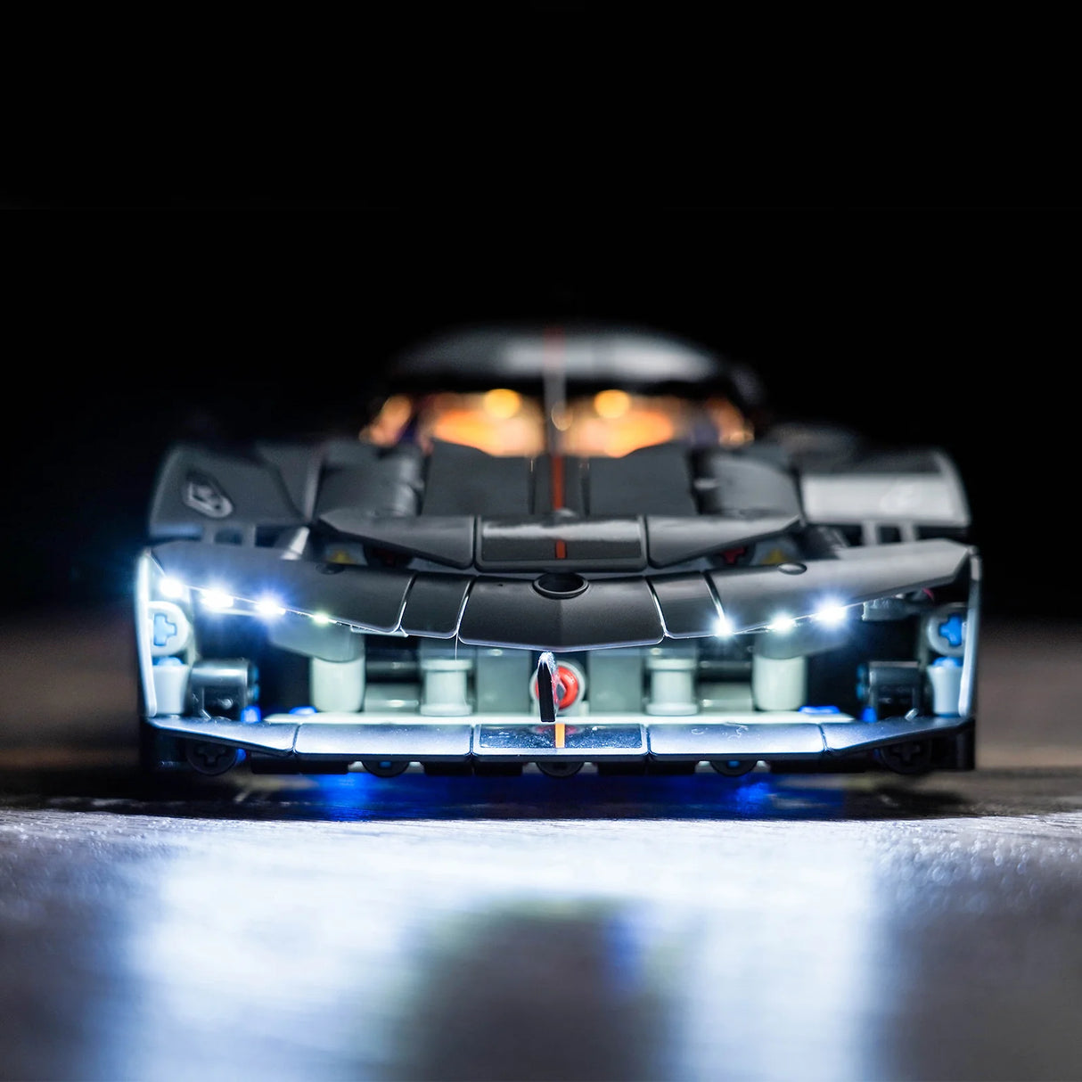 Frontalansicht eines schwarzen Modellautos mit eingeschalteten LED Scheinwerfern