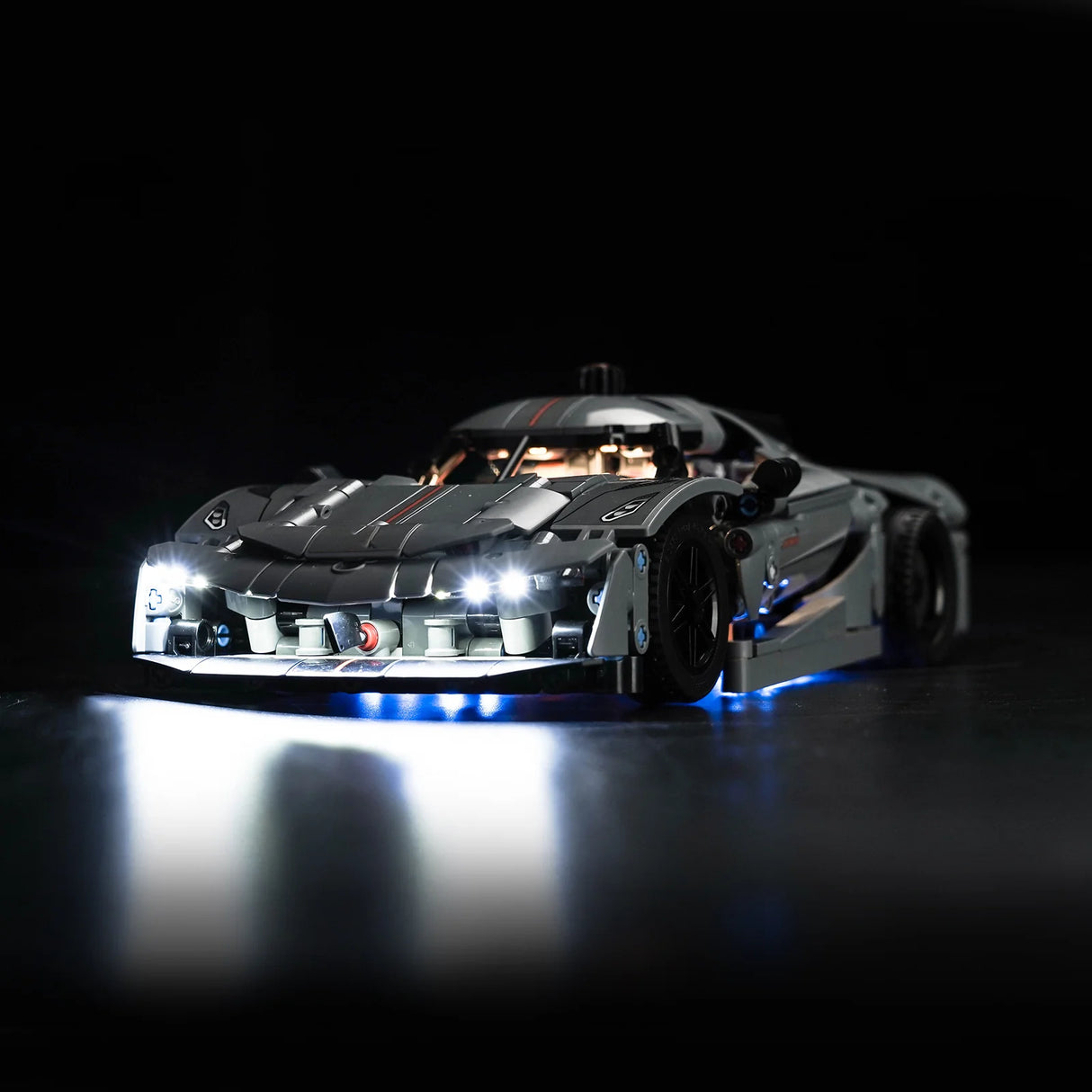 Graues Modellauto mit eingeschalteter LED Beleuchtung vor schwarzem Hintergrund