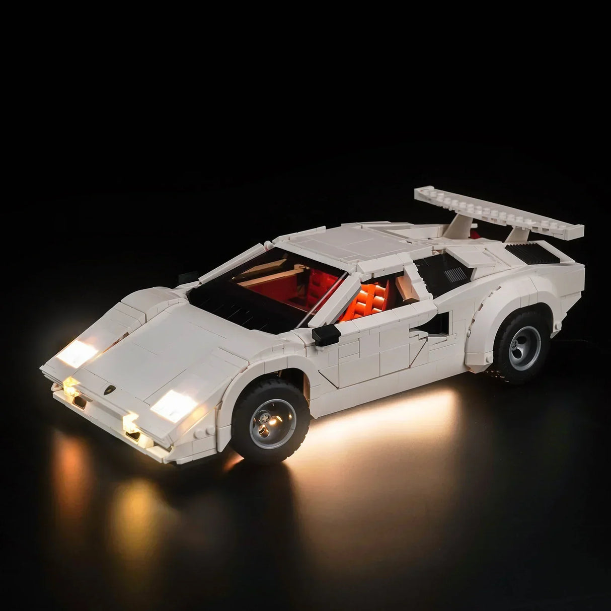 Weißes Lamborghini Modellauto aus Klemmbausteinen mit eingeschalteter LED Beleuchtung vor schwarzem Hintergrund