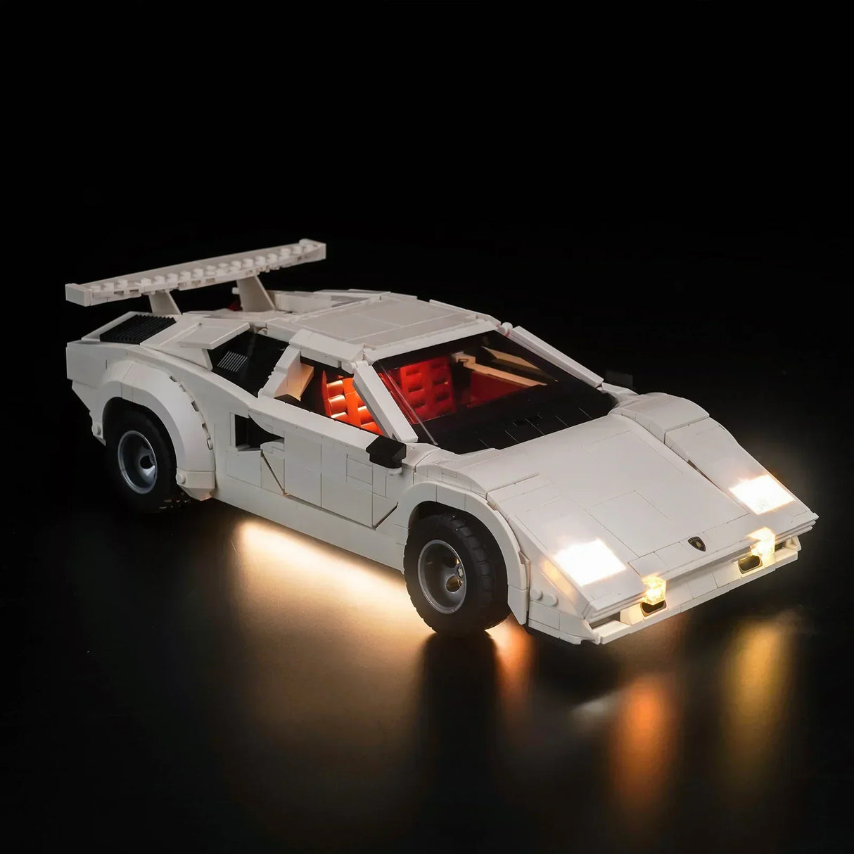Weißes Lamborghini Countach Modell aus Klemmbausteinen mit eingeschalteter LED Beleuchtung vor schwarzem Hintergrund
