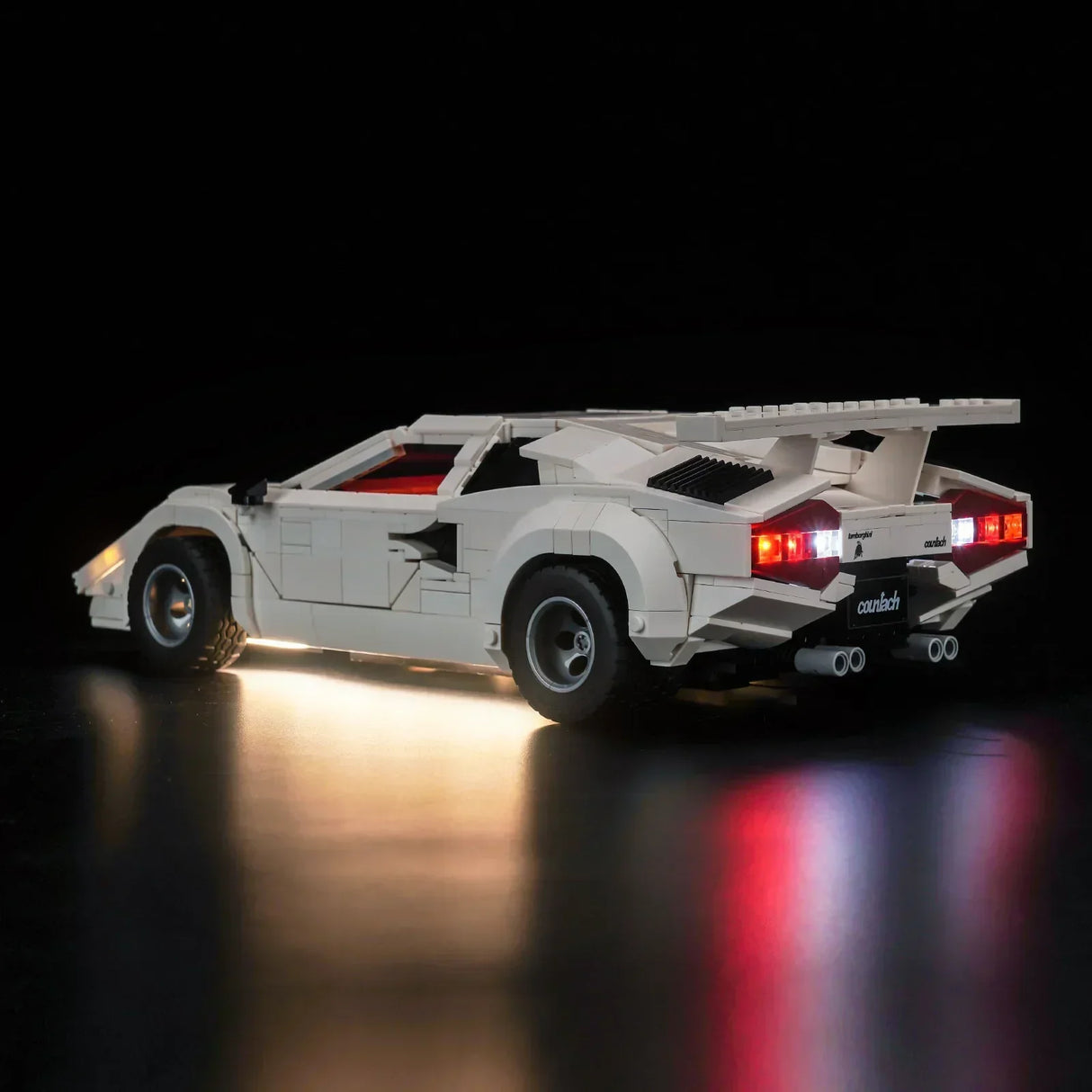 Weißes Lamborghini Countach Modell aus Klemmbausteinen mit beleuchteten Rücklichtern vor schwarzem Hintergrund