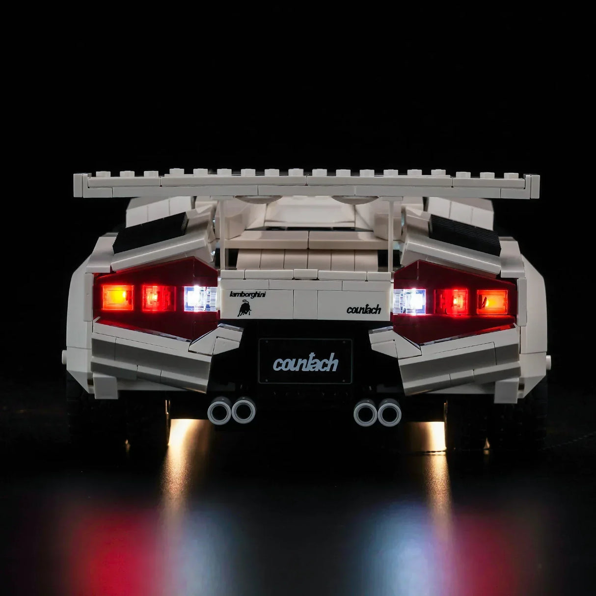 Heckansicht eines weißen Lego Lamborghini Countach mit leuchtenden Rücklichtern vor schwarzem Hintergrund
