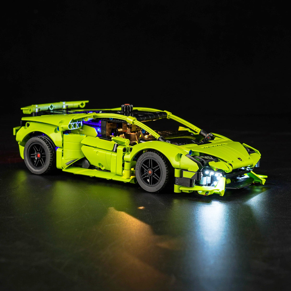 Gruenes Lamborghini Modellauto aus Klemmbausteinen mit eingeschalteter LED Beleuchtung vor schwarzem Hintergrund
