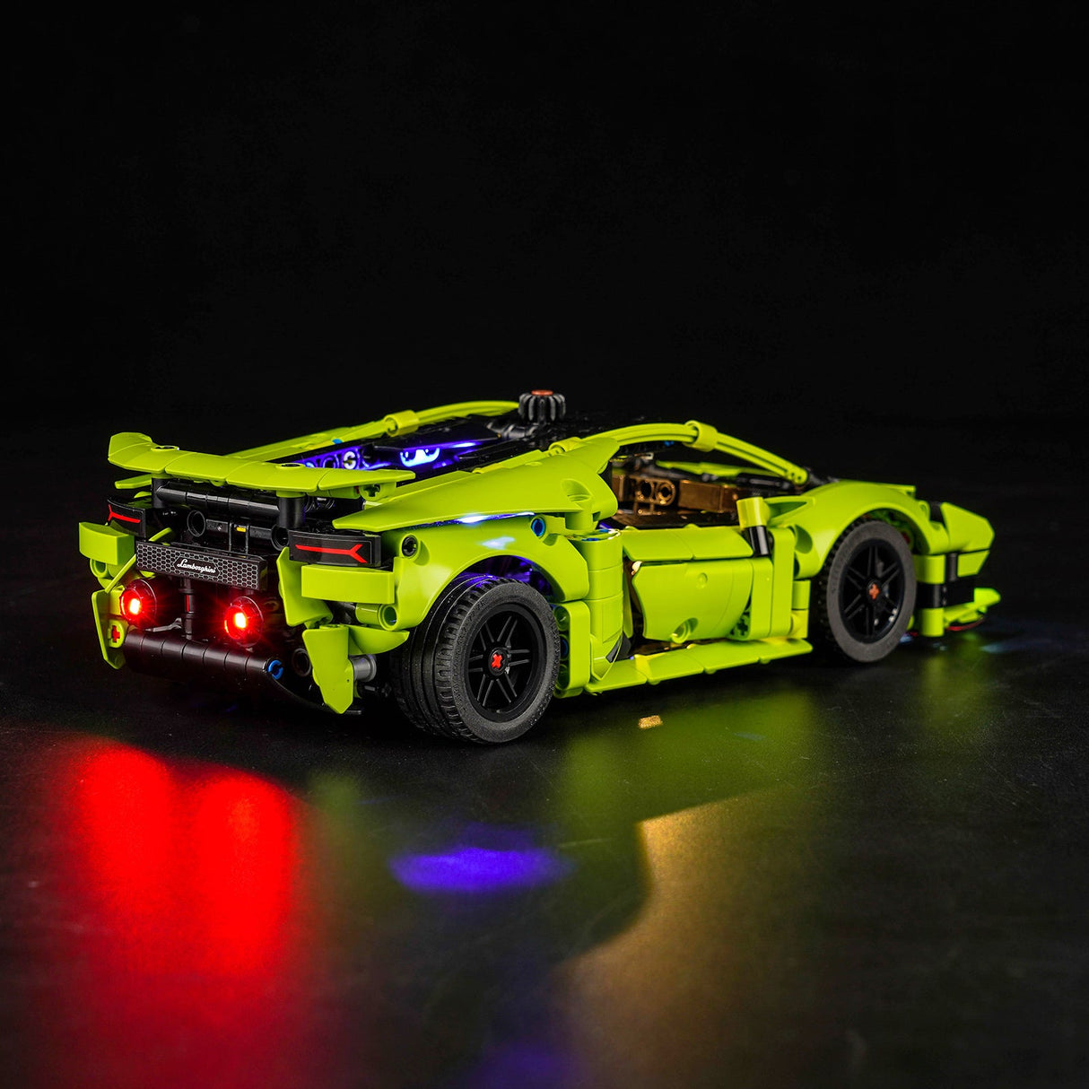 Gruenes Lego Lamborghini Modellauto mit leuchtenden roten Ruecklichtern vor schwarzem Hintergrund