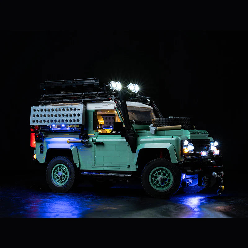 Beleuchtetes Lego Modell eines grünen Land Rover Defender vor schwarzem Hintergrund