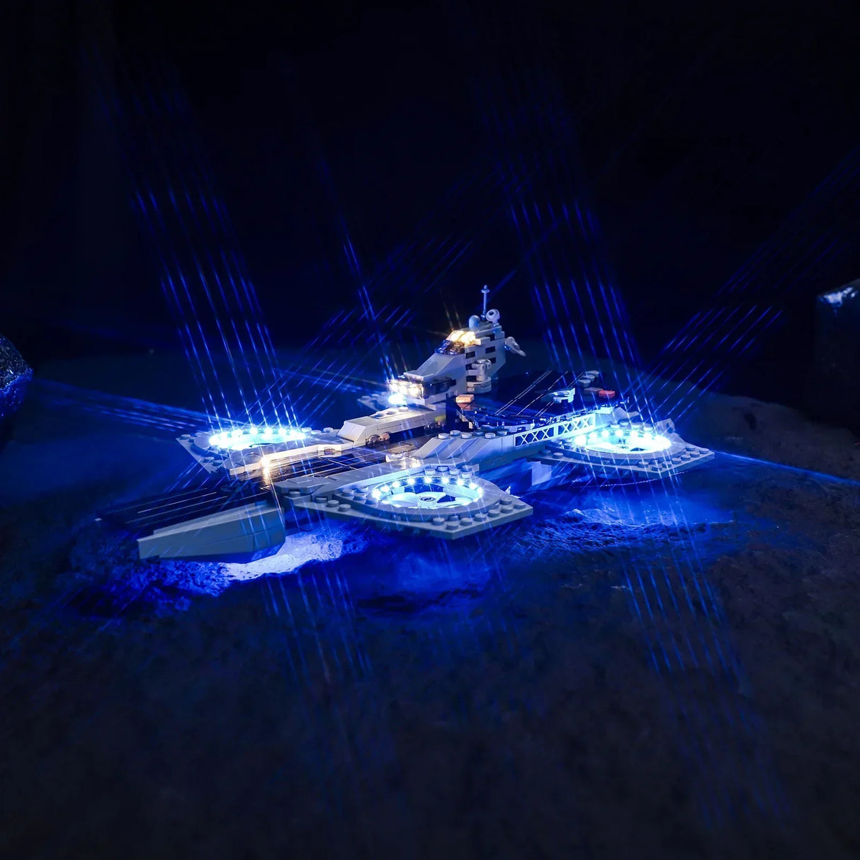 Beleuchtetes Modell eines Raumschiffs mit blauen Lichtstrahlen auf dunklem Untergrund