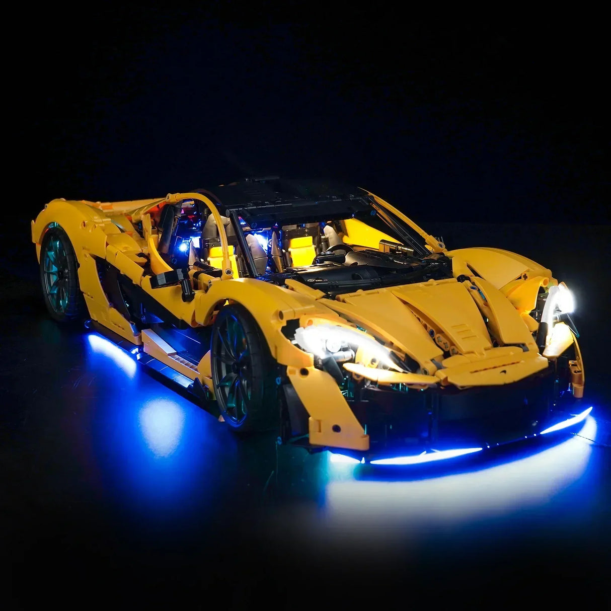 Gelbes Lego Modellauto mit blauer LED Beleuchtung vor schwarzem Hintergrund
