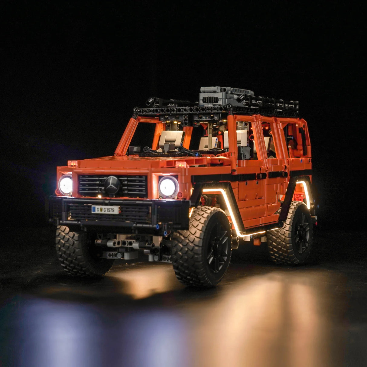 Orangefarbenes Mercedes G-Klasse Modell aus Klemmbausteinen mit eingeschalteter LED Beleuchtung vor schwarzem Hintergrund