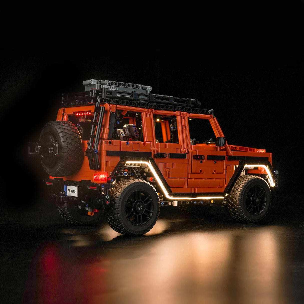 Orangefarbenes Mercedes G-Klasse Modell aus Klemmbausteinen mit beleuchteten Radläufen vor schwarzem Hintergrund