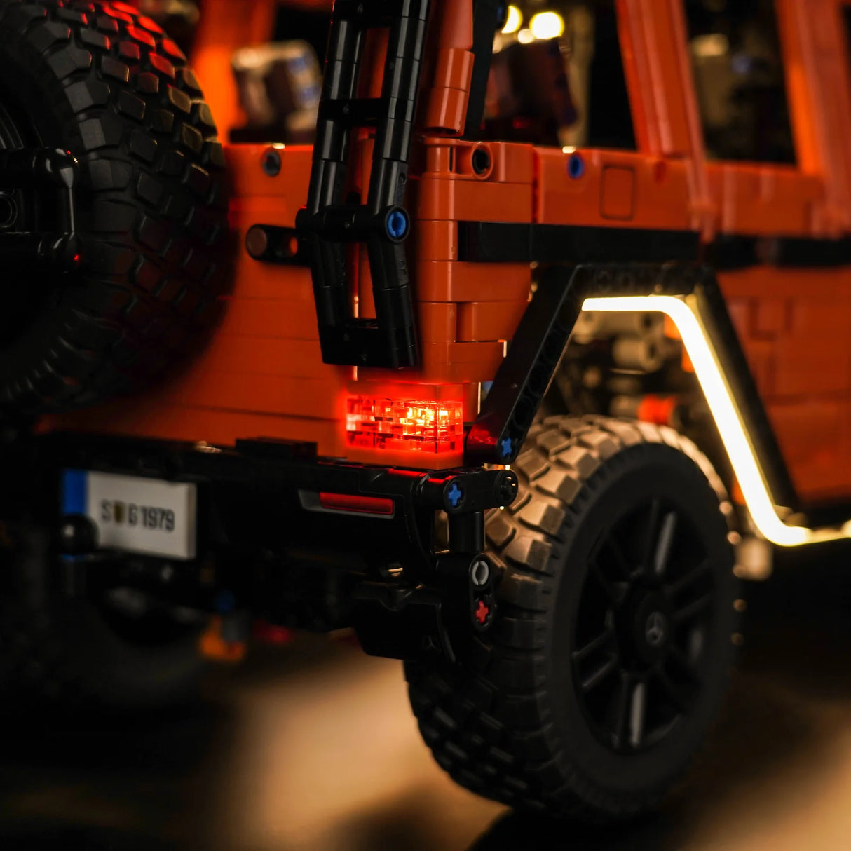 Heckansicht eines orangefarbenen Modellautos mit leuchtenden Rücklichtern und Ersatzrad