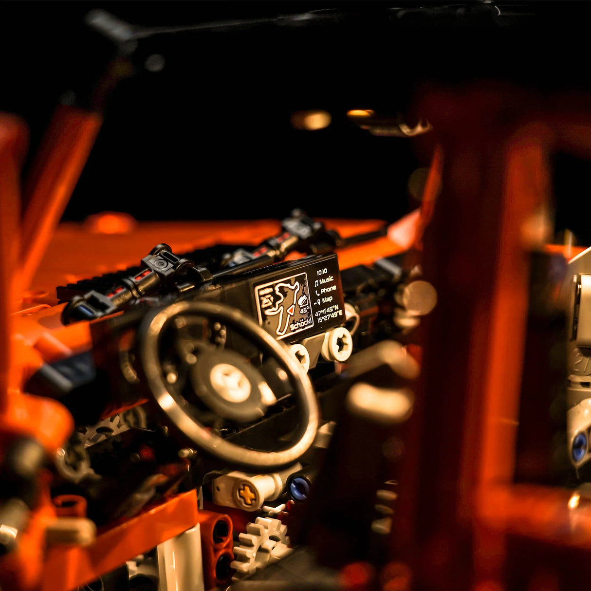 Detailansicht des Cockpits eines orangefarbenen Modellautos mit Lenkrad und digitalem Display
