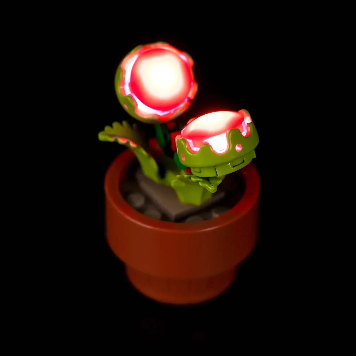 Detailansicht der LEGO Venusfliegenfalle aus dem Set 10329 mit eingebauter LED-Beleuchtung, die die roten Fangblätter von innen heraus intensiv leuchten lässt.