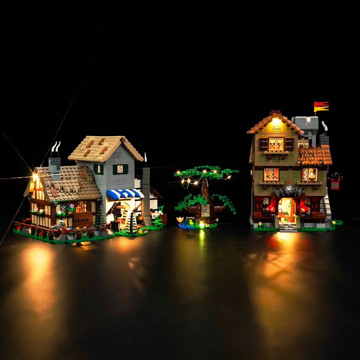 Beleuchtetes Lego Mittelalterdorf mit zwei Häusern und einem Baum vor schwarzem Hintergrund