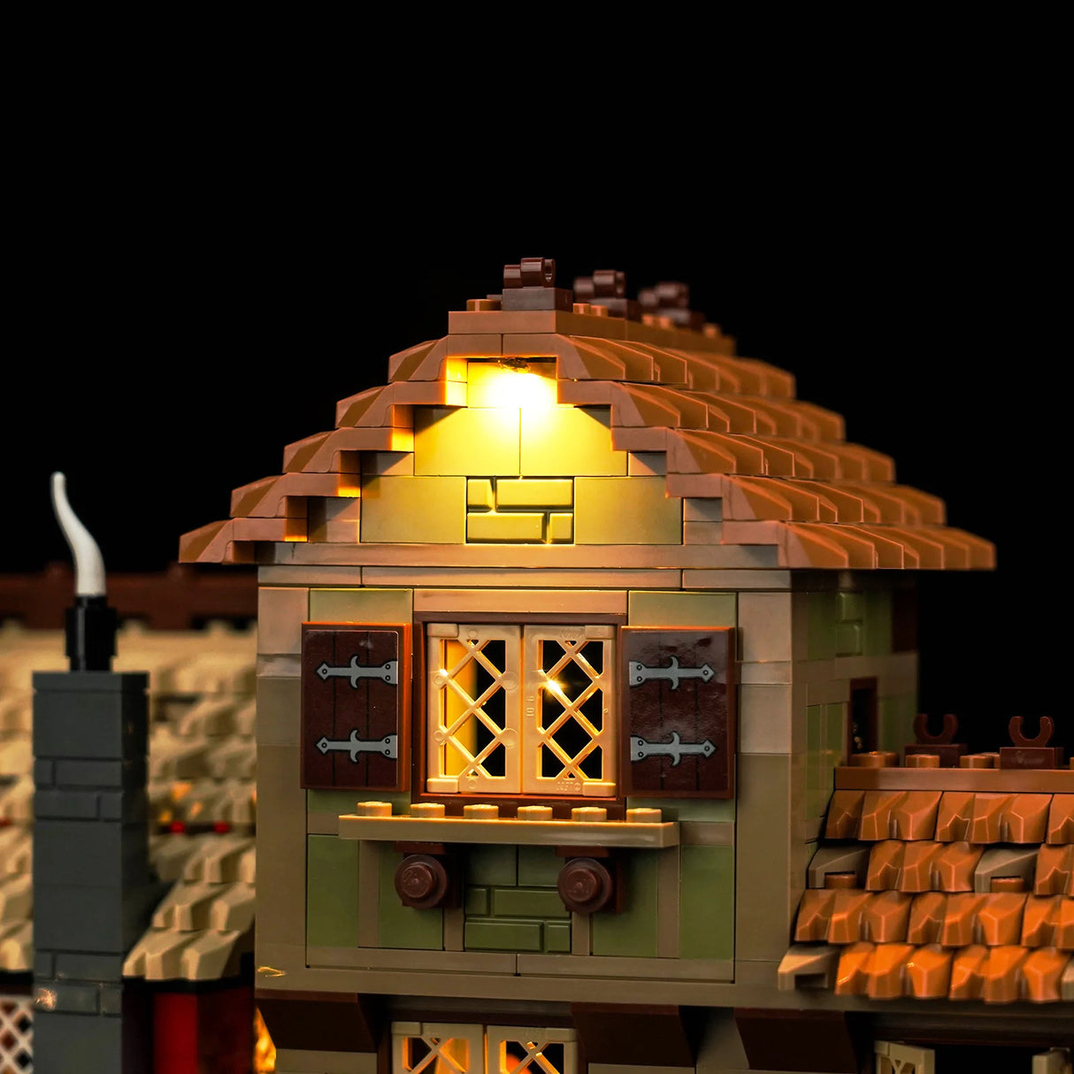 Beleuchtetes Lego Hausmodell mit braunem Dach und Fenster vor schwarzem Hintergrund