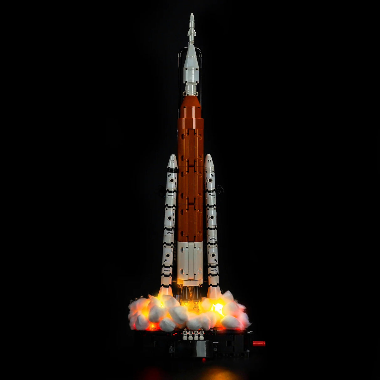 Ein orange-weißes Raketenmodell mit leuchtendem Startrauch auf schwarzem Hintergrund
