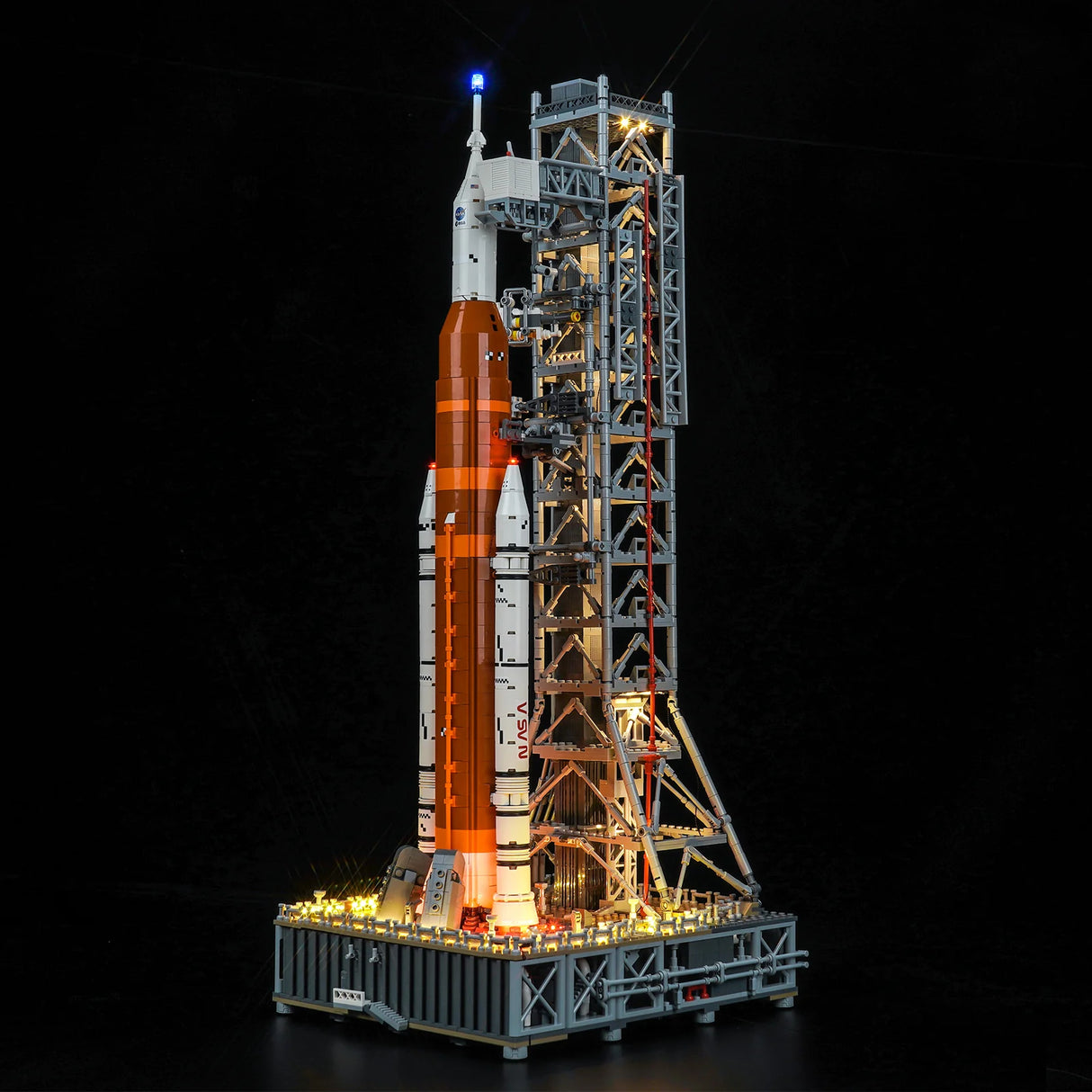 Beleuchtetes Lego Modell einer Weltraumrakete auf einer Startrampe vor schwarzem Hintergrund