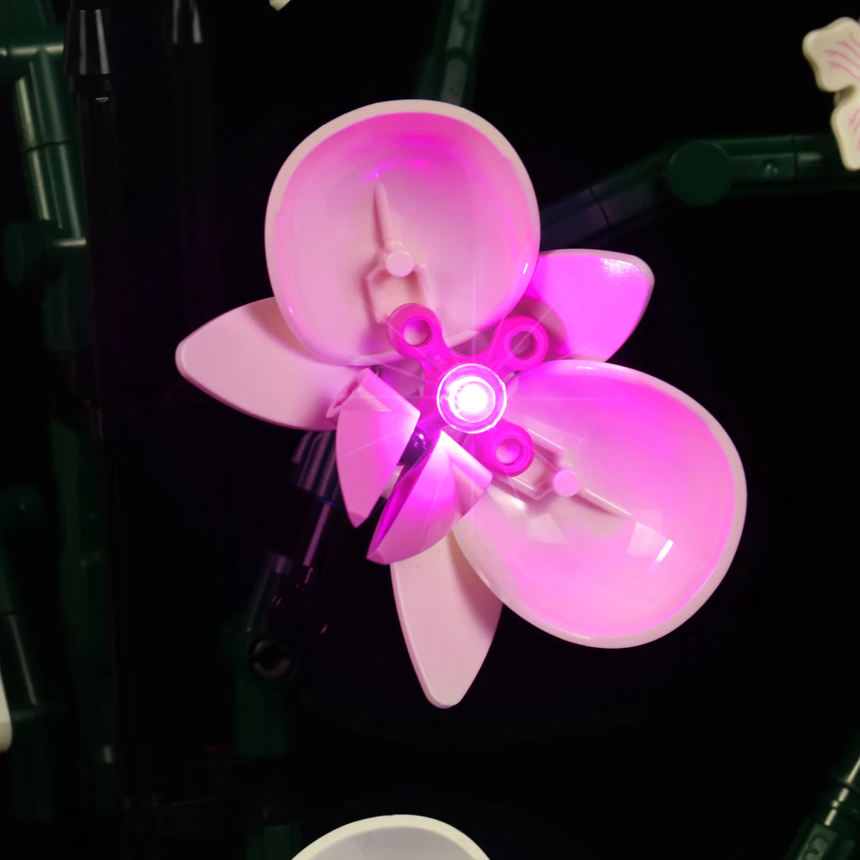 Rosa Lego Blume mit leuchtender LED Mitte vor schwarzem Hintergrund