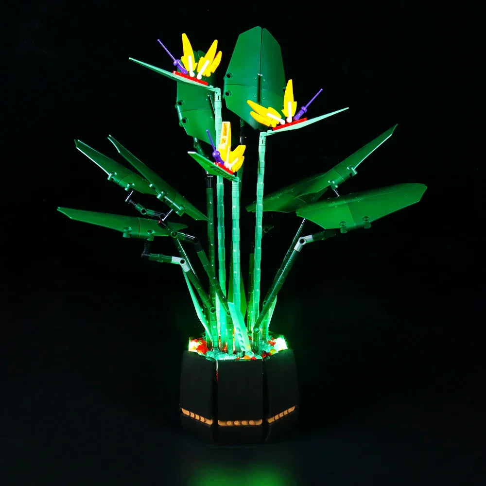 Beleuchtetes Modell einer Paradiesvogelblume aus Klemmbausteinen in einem schwarzen Topf vor schwarzem Hintergrund